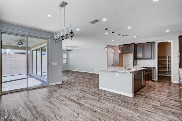 kitchen with a sink, wood finished floors, visible vents, and a ceiling fan