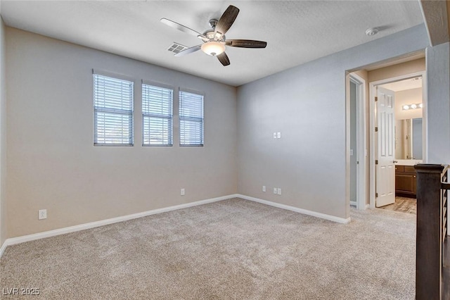 spare room with a ceiling fan, light carpet, visible vents, and baseboards