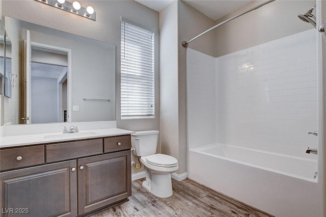 bathroom with bathing tub / shower combination, toilet, vanity, wood finished floors, and baseboards