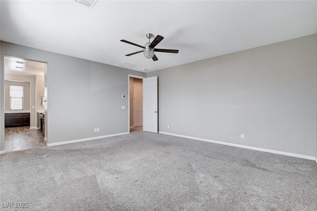 carpeted spare room featuring a ceiling fan, visible vents, and baseboards