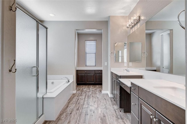 full bathroom with a sink, a stall shower, a garden tub, and wood finished floors