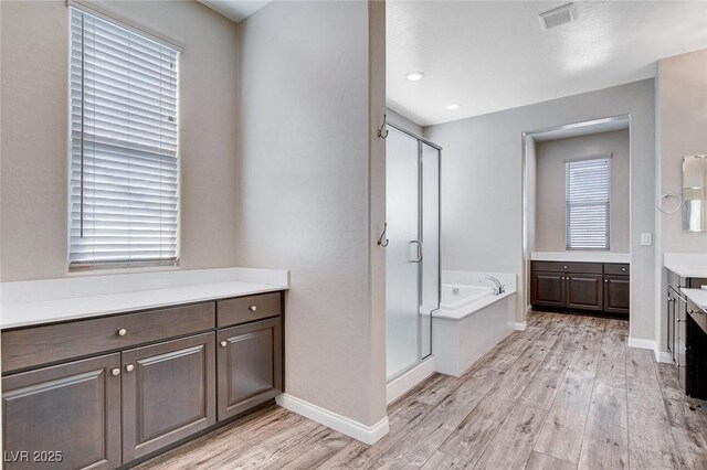 full bath featuring visible vents, vanity, a shower stall, wood finished floors, and a bath