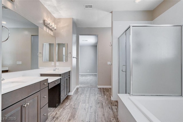 full bath featuring wood finished floors, vanity, visible vents, baseboards, and a stall shower