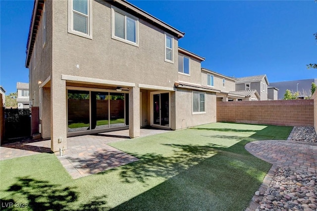 rear view of house with a yard, a patio area, a fenced backyard, and stucco siding