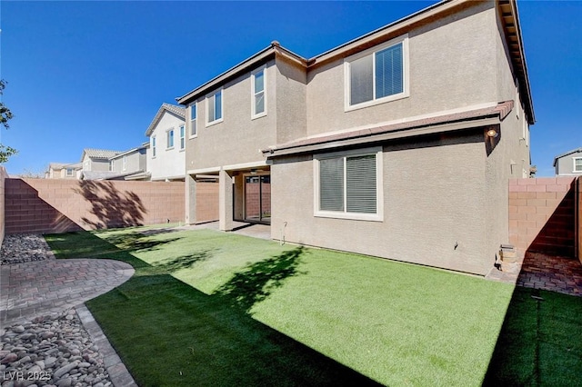 rear view of house with a patio, a lawn, a fenced backyard, and stucco siding