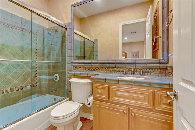 full bath with decorative backsplash, shower / bath combination with glass door, vanity, and toilet