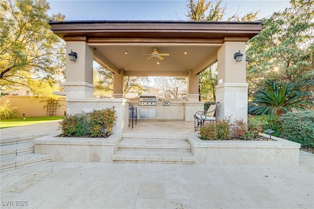 view of patio / terrace with ceiling fan, fence, a grill, and an outdoor kitchen