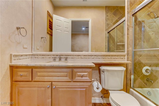 full bathroom with toilet, bath / shower combo with glass door, and vanity