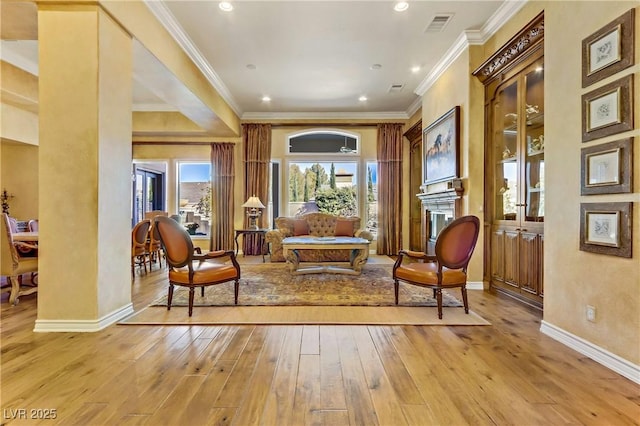 living area featuring baseboards, ornamental molding, and light wood-style floors