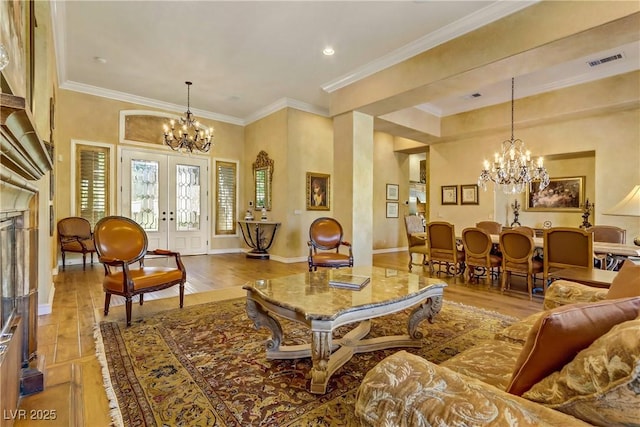 living area with a chandelier, french doors, visible vents, and ornamental molding