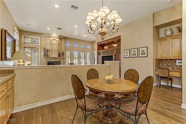 dining area featuring visible vents, baseboards, light wood-style flooring, a fireplace, and recessed lighting