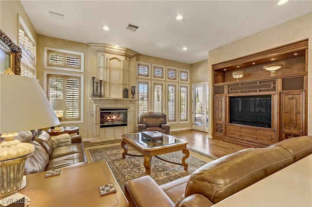 living area with recessed lighting, a large fireplace, wood finished floors, visible vents, and baseboards