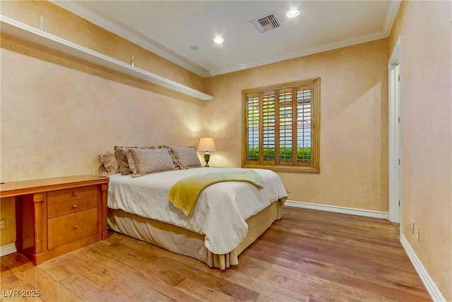 bedroom with baseboards, ornamental molding, visible vents, and light wood-style floors