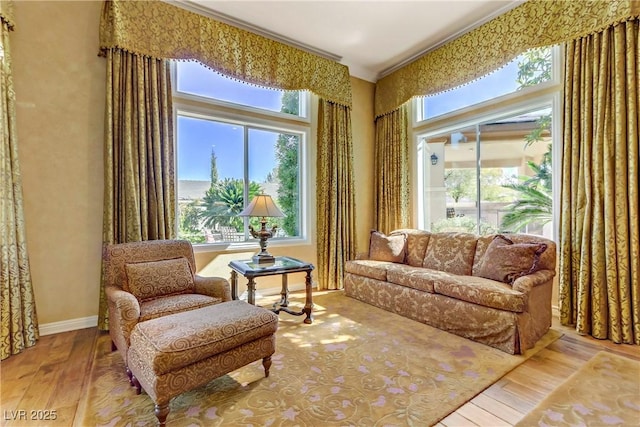 sitting room with crown molding, baseboards, and wood finished floors