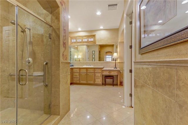 bathroom with a stall shower, visible vents, tile walls, and vanity