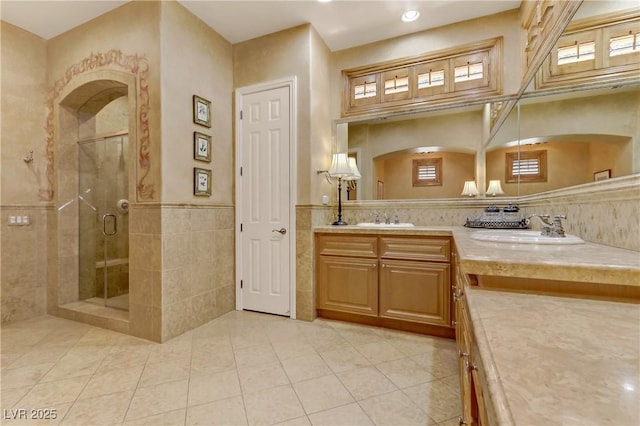 interior space featuring a wainscoted wall, a sink, tile walls, and a shower stall