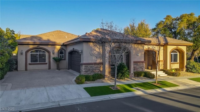 mediterranean / spanish house featuring a garage, stone siding, driveway, and stucco siding