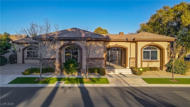 view of front of house with stone siding, concrete driveway, and stucco siding