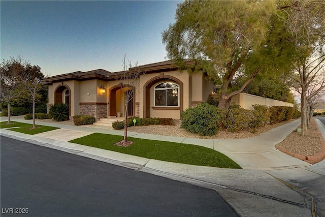 mediterranean / spanish house with stone siding and stucco siding