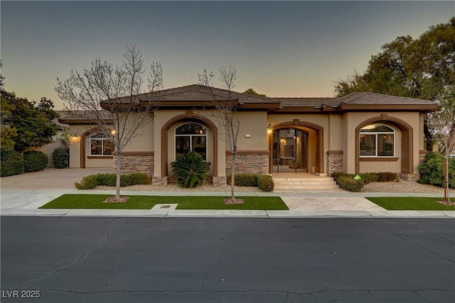 mediterranean / spanish home with stone siding, driveway, and stucco siding