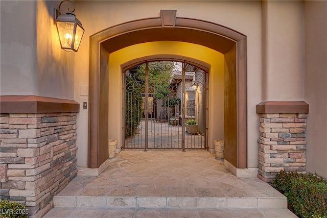 entrance to property with stone siding and a gate