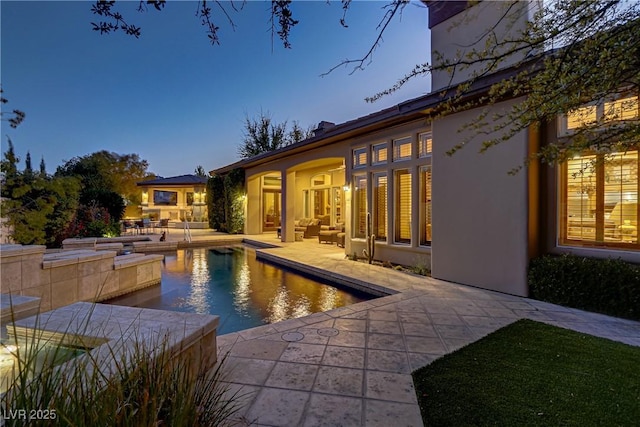 pool at dusk featuring a patio area and an outdoor pool