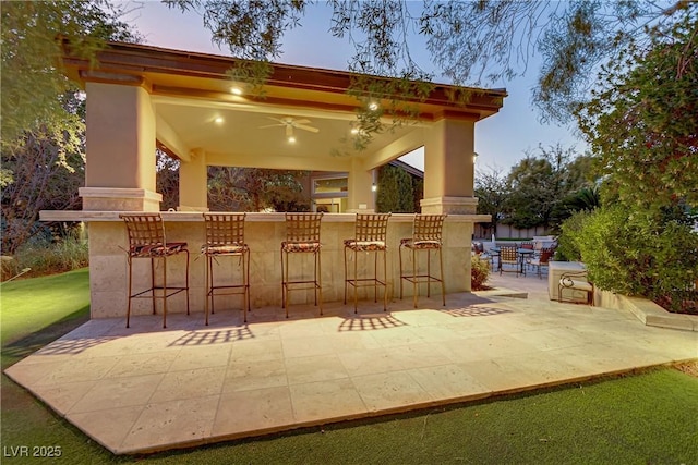 view of patio with outdoor dry bar and a ceiling fan