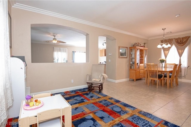 interior space with arched walkways, crown molding, tile patterned floors, baseboards, and ceiling fan with notable chandelier