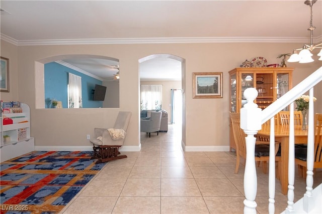 entryway featuring arched walkways, crown molding, baseboards, and light tile patterned floors