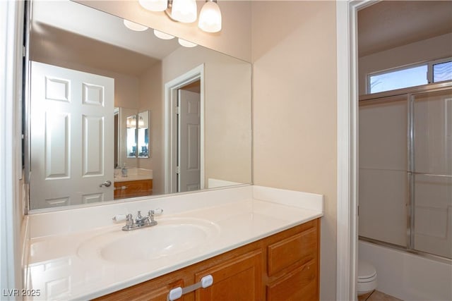 full bath with toilet, bath / shower combo with glass door, and vanity