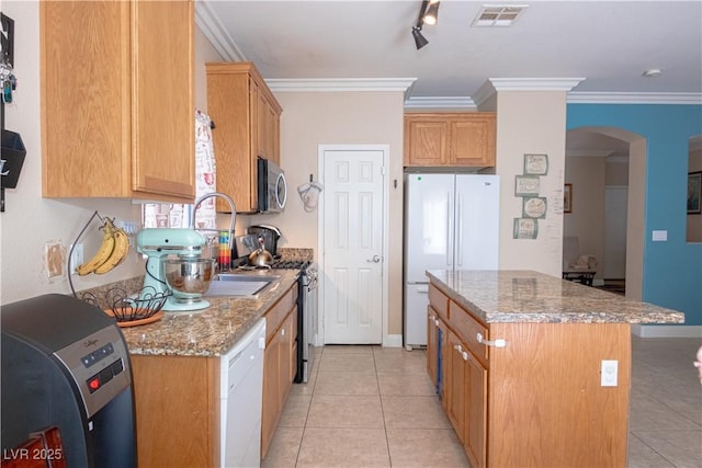 kitchen featuring light tile patterned floors, arched walkways, appliances with stainless steel finishes, ornamental molding, and a center island