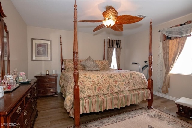 bedroom with a ceiling fan, baseboards, visible vents, and wood finished floors