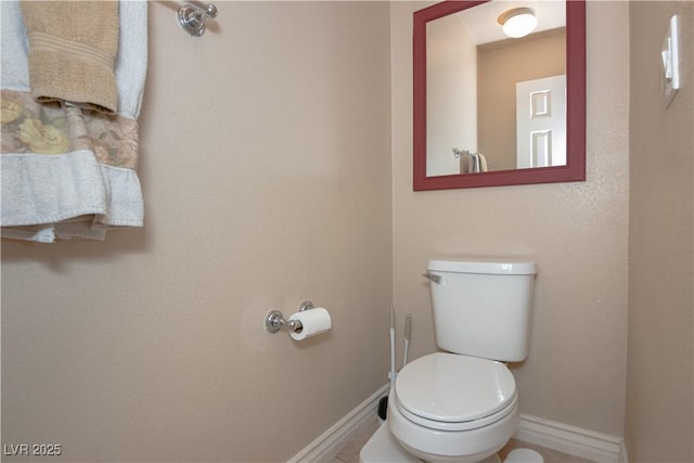 half bath featuring toilet and baseboards