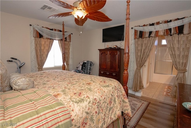 bedroom featuring ceiling fan, multiple windows, visible vents, and wood finished floors