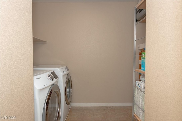 clothes washing area with laundry area, washer and clothes dryer, light tile patterned flooring, and baseboards