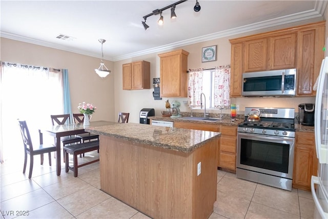 kitchen with visible vents, a kitchen island, appliances with stainless steel finishes, ornamental molding, and a sink