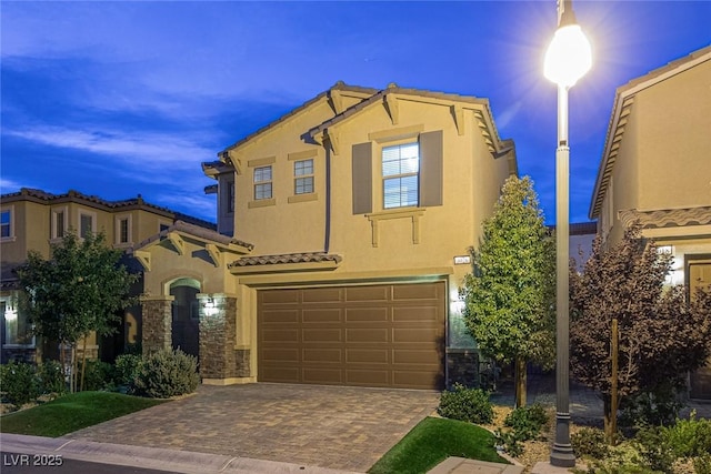 view of front of property with an attached garage, a tile roof, decorative driveway, and stucco siding