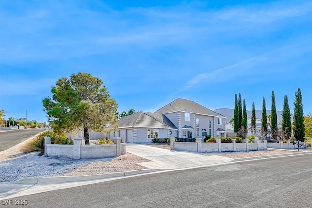 view of front of property with concrete driveway, fence, and an attached garage