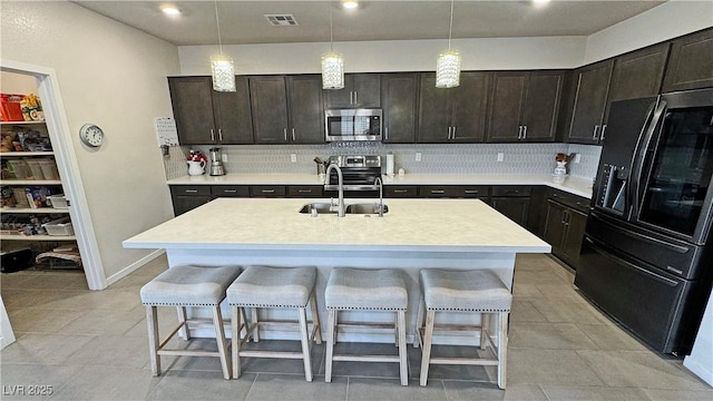 kitchen with a breakfast bar area, stainless steel appliances, a sink, light countertops, and decorative backsplash