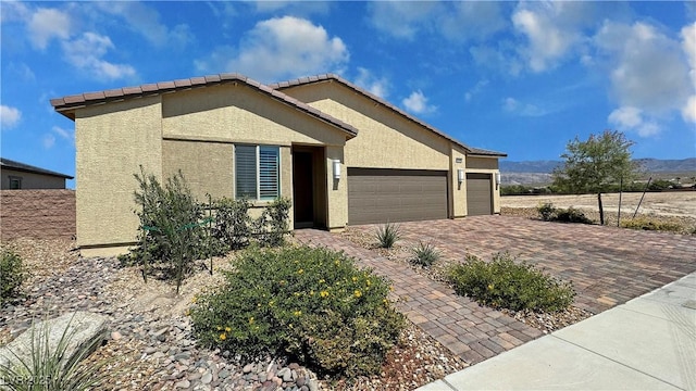 ranch-style home with an attached garage, decorative driveway, and stucco siding