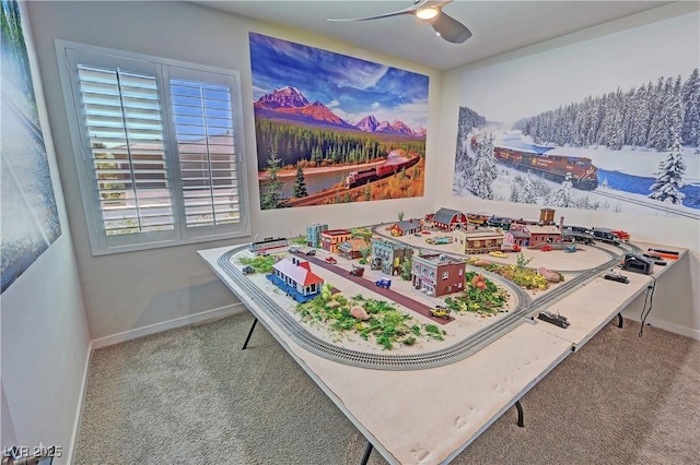 recreation room with carpet, ceiling fan, and baseboards