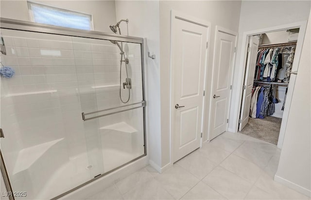full bathroom featuring tile patterned flooring, a walk in closet, and a shower stall