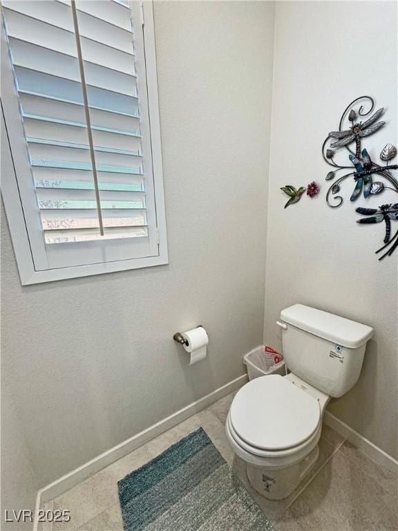 bathroom with toilet, baseboards, and tile patterned floors