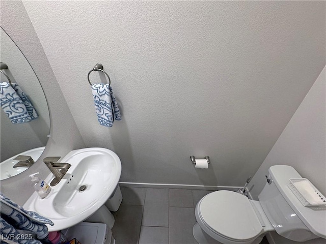 bathroom featuring toilet, a sink, baseboards, and tile patterned flooring