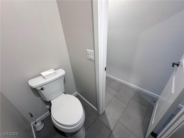 bathroom featuring tile patterned floors, toilet, and baseboards
