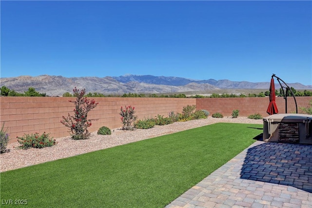 view of yard with a patio, a mountain view, a fenced backyard, and a hot tub