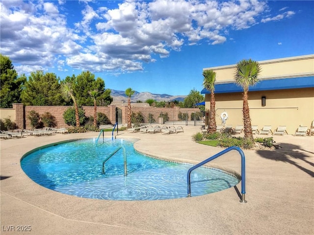 community pool featuring fence, a mountain view, and a patio area