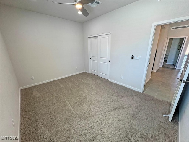 unfurnished bedroom featuring a closet, carpet floors, baseboards, visible vents, and ceiling fan
