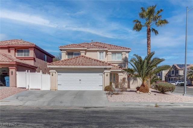 mediterranean / spanish home featuring fence, a tiled roof, an attached garage, and stucco siding