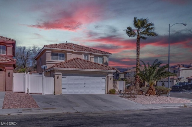 view of front facade featuring a tile roof, stucco siding, a gate, a garage, and driveway